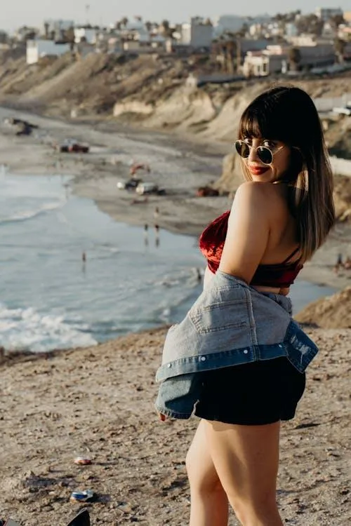 Woman with Sunglasses Standing by the Beach on a Sunny Day