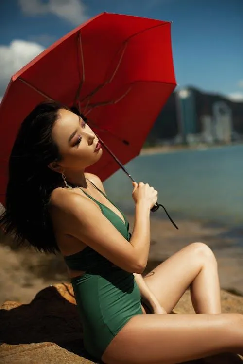 Woman in a Swimsuit Posing Under a Red Umbrella Outdoors