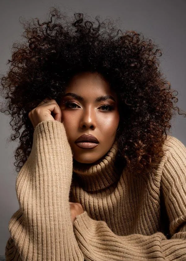 Woman with a Voluminous Curly Hair in a Cozy Sweater Poses