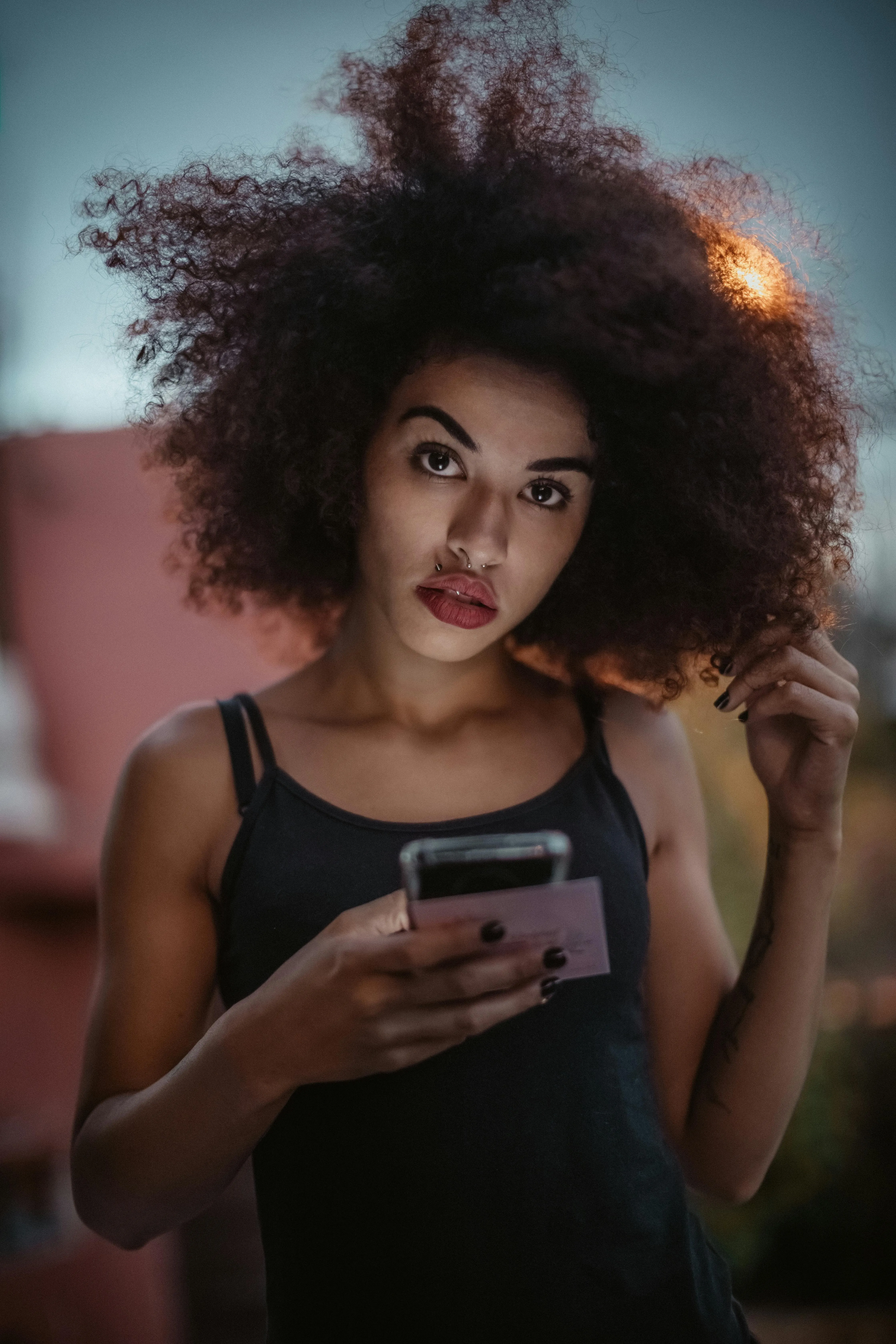 Woman with a Voluminous Hair Using Phone in a Casual Outfit