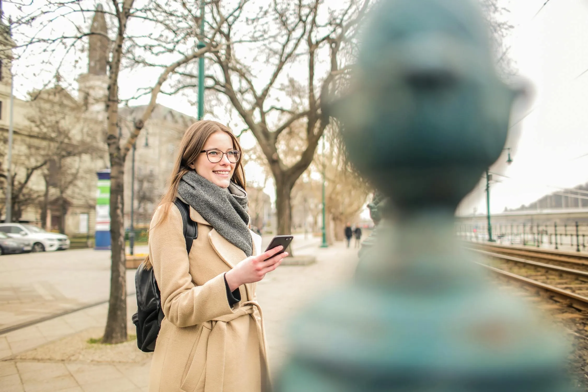 Woman Walking on a City Street Holding a Phone and Smiling
