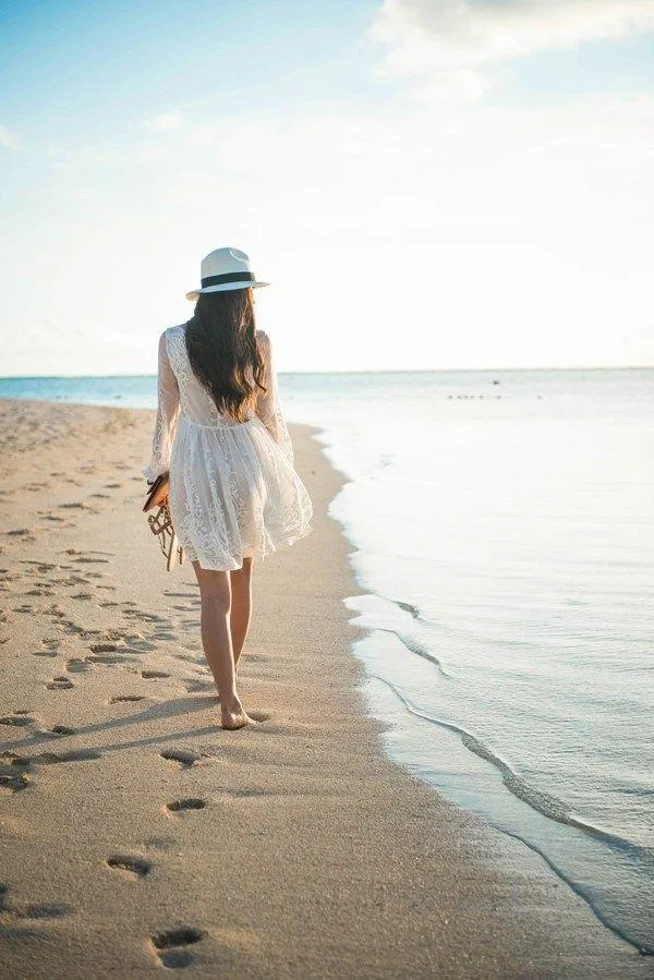 Woman Walking on the Beach in a White Dress and Hat Image