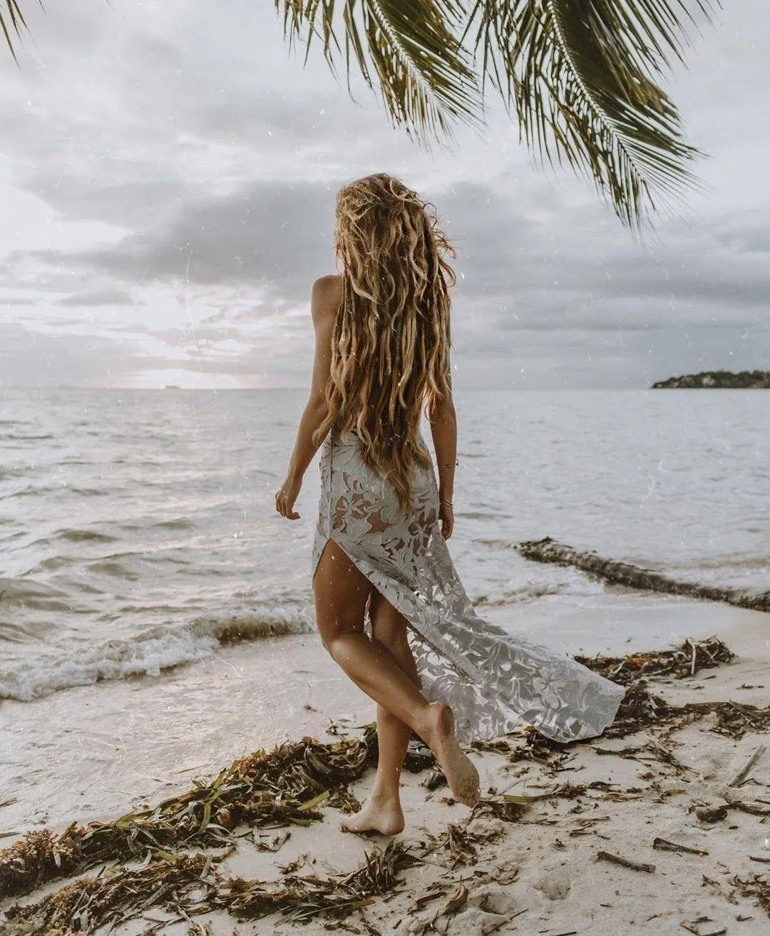 Woman Walking by the Sea with Waves Hitting the Shore Image