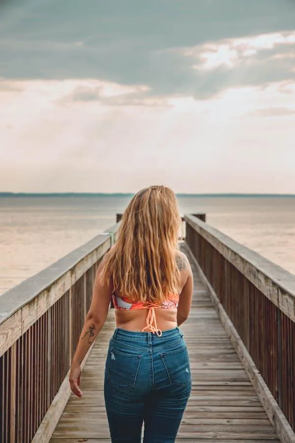Woman Walking on Wooden Pier Toward the Calm Sea Horizon