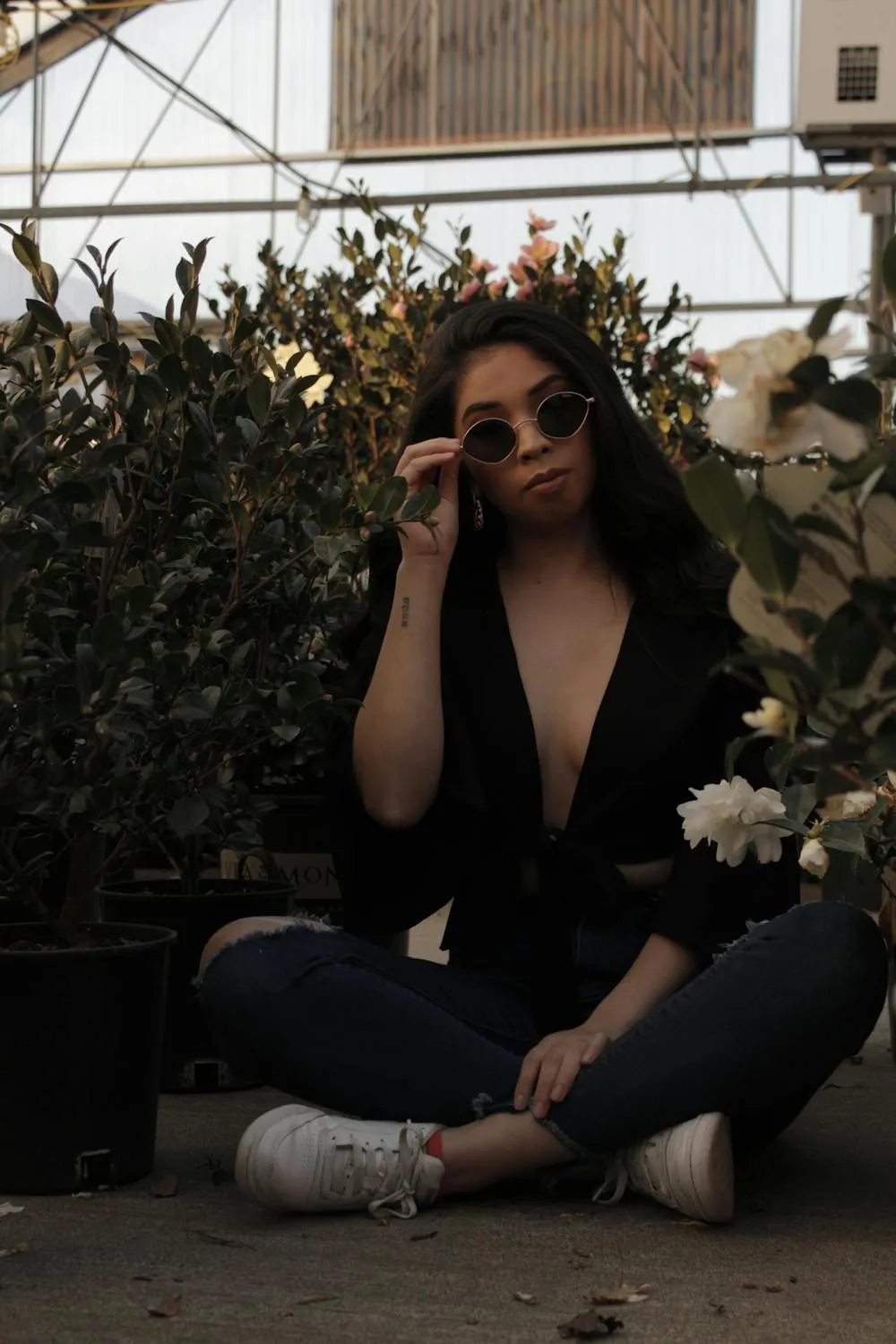 Woman Wearing Black Top and Jeans Posing in a Garden Setting