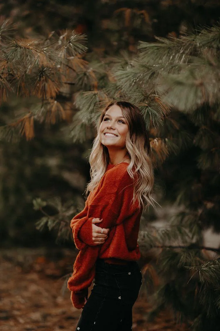 Woman Wearing Red Sweater Smiling Outdoors in Autumn Forest