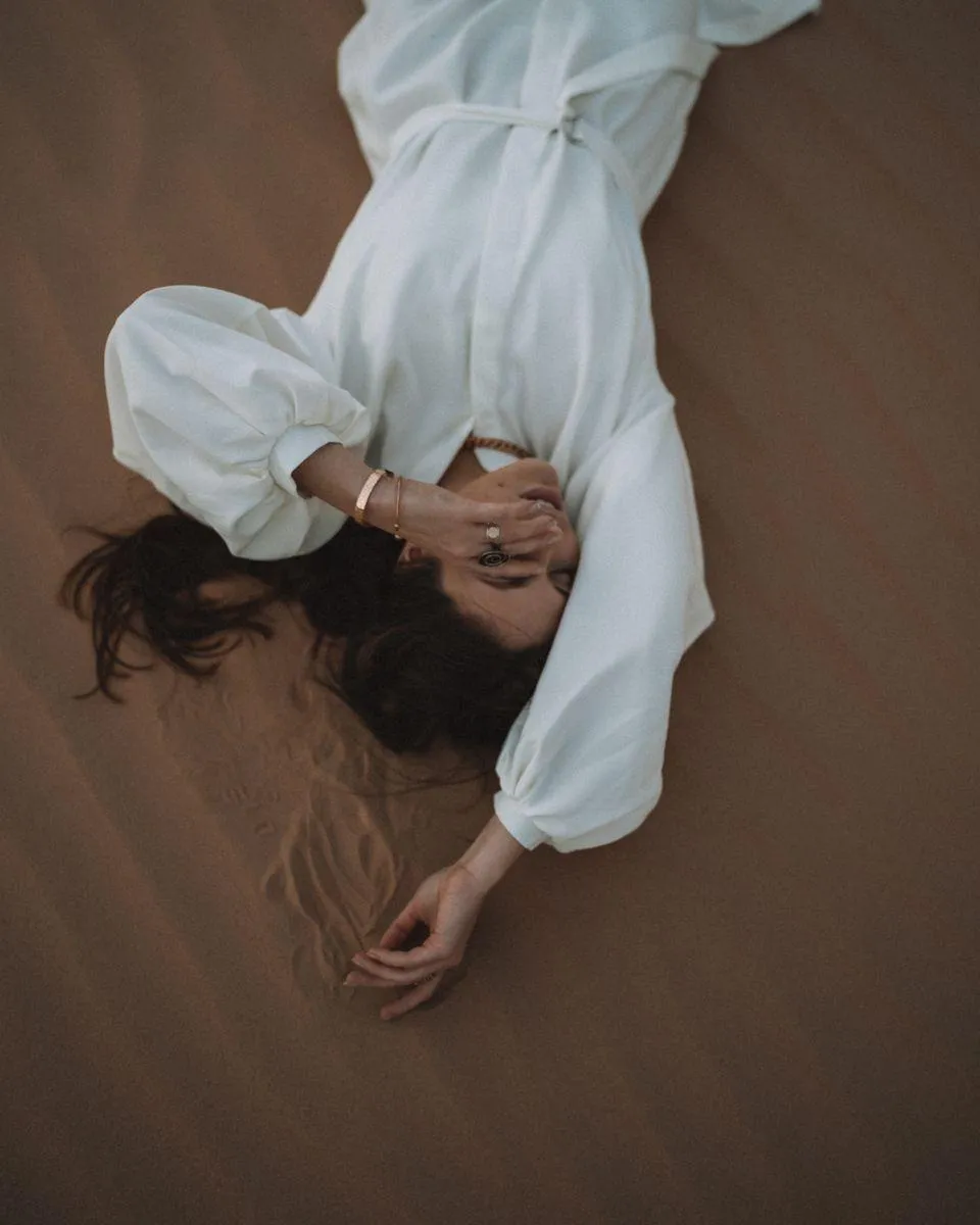 Woman in a White Dress Lying Sideways on a Brown Background