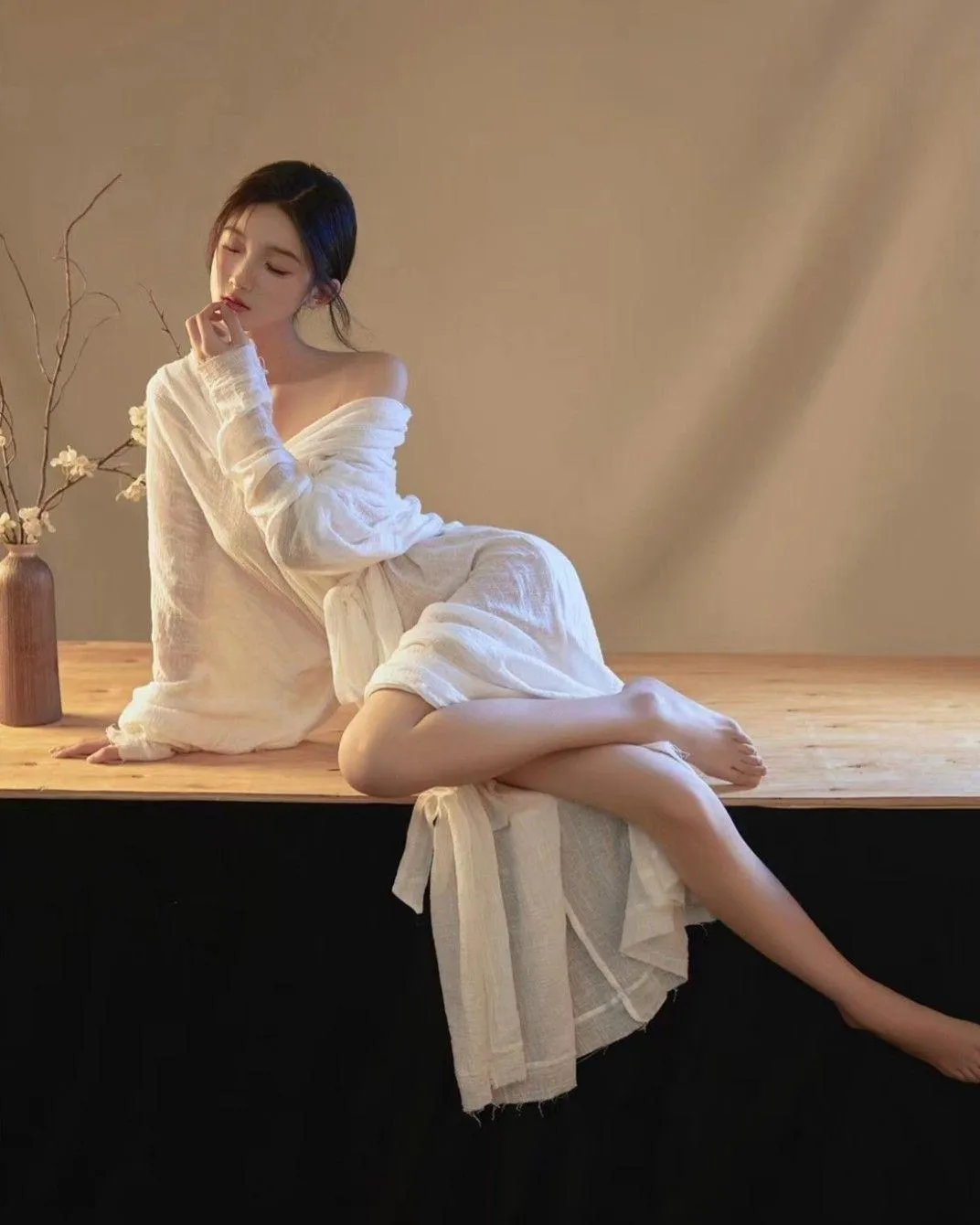 Woman in a White Dress Posing Gracefully on a Wooden Bench