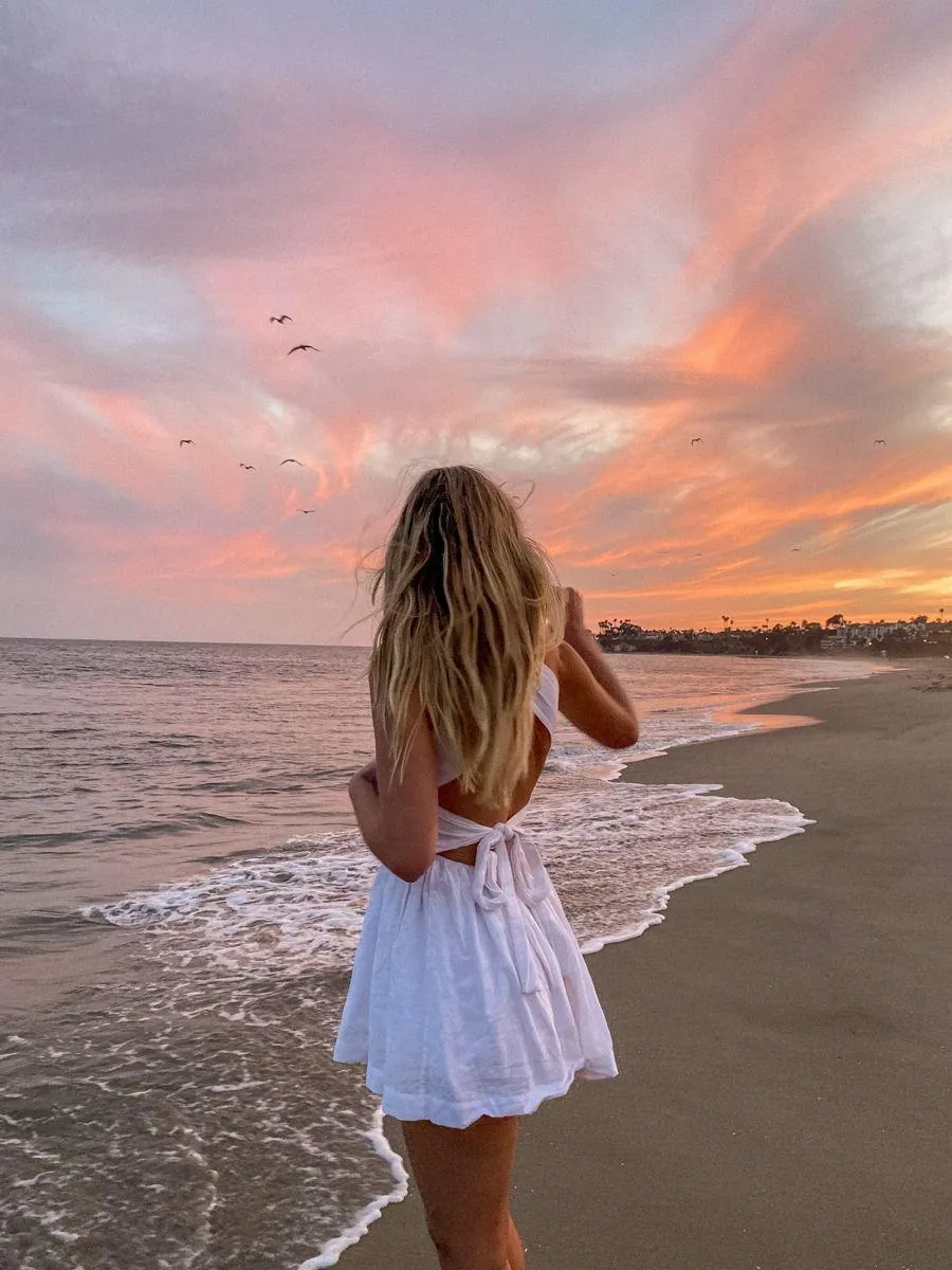 Woman in a White Dress Standing Alone on the Beach Shore