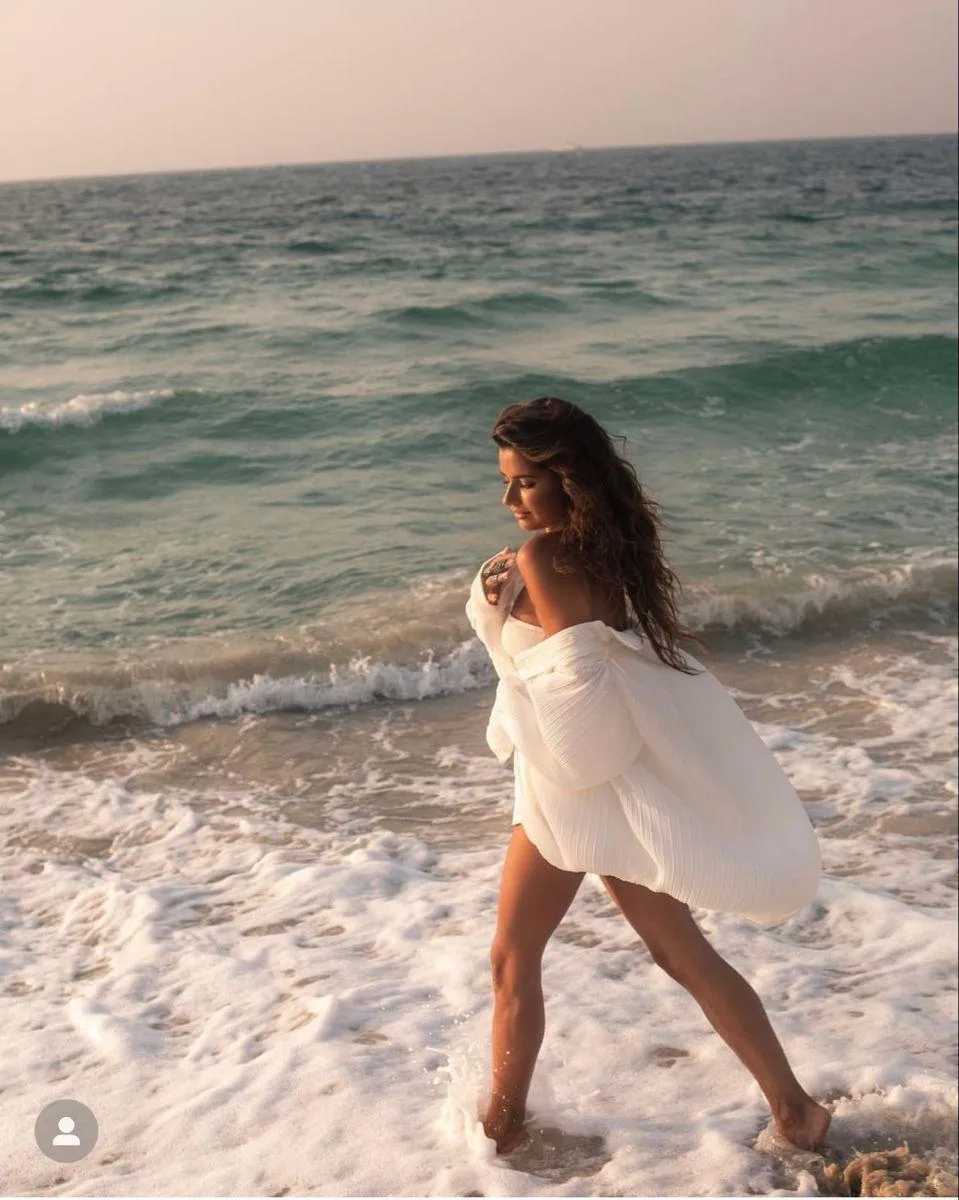 Woman in a White Dress Walking by the Ocean with Soft Waves