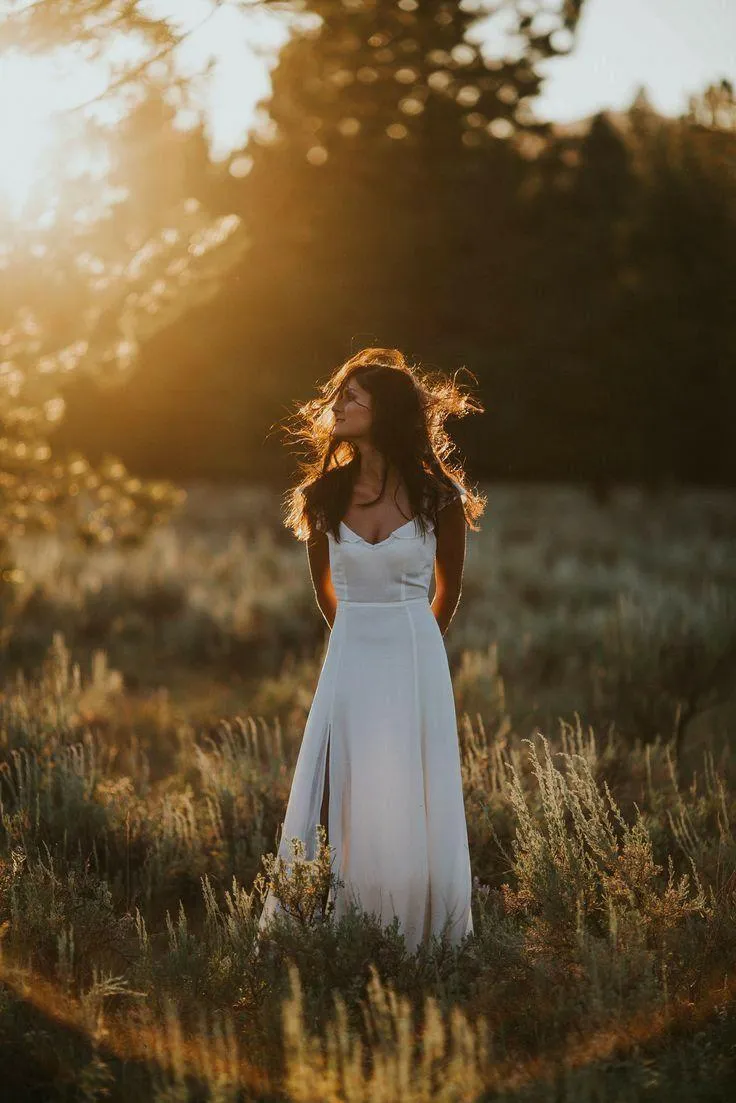 Woman in a White Dress Walking Through a Quiet Grassy Field