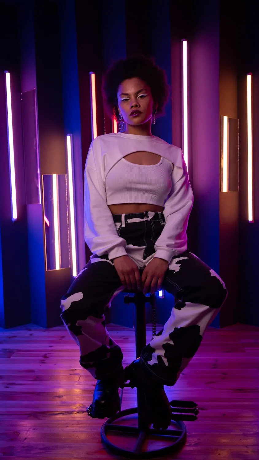 Woman in White Outfit Posing Dramatically Under Neon Lights