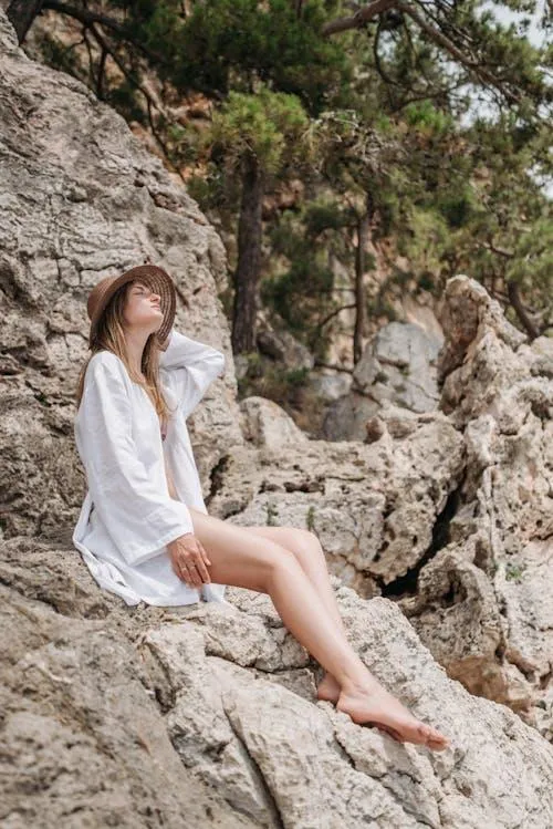 Woman in White Outfit Relaxing on a Rocky Outdoor Cliff