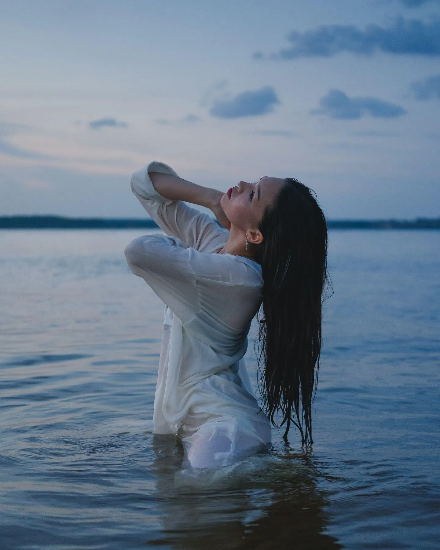 Woman in a White Shirt Posing in the Water During Sunset