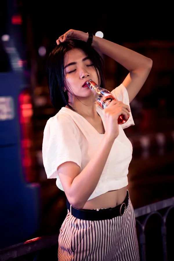 Woman in a White Shirt and Striped Pants Adjusting Her Hair