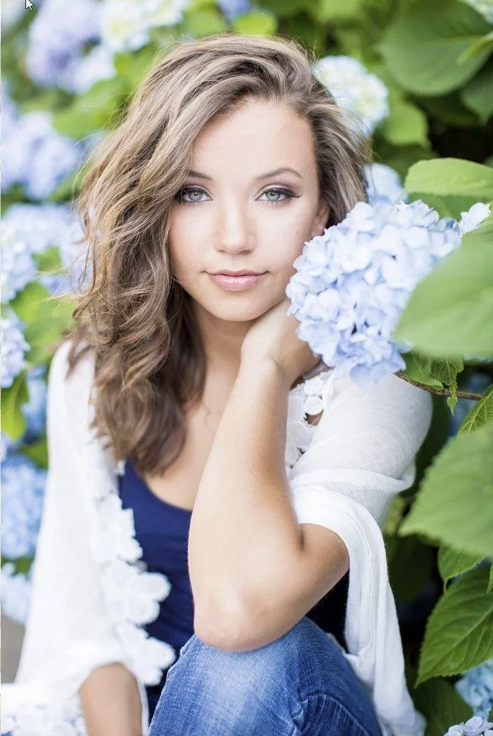 Woman in a White Top Posing Under Blue Sky with Clouds Image