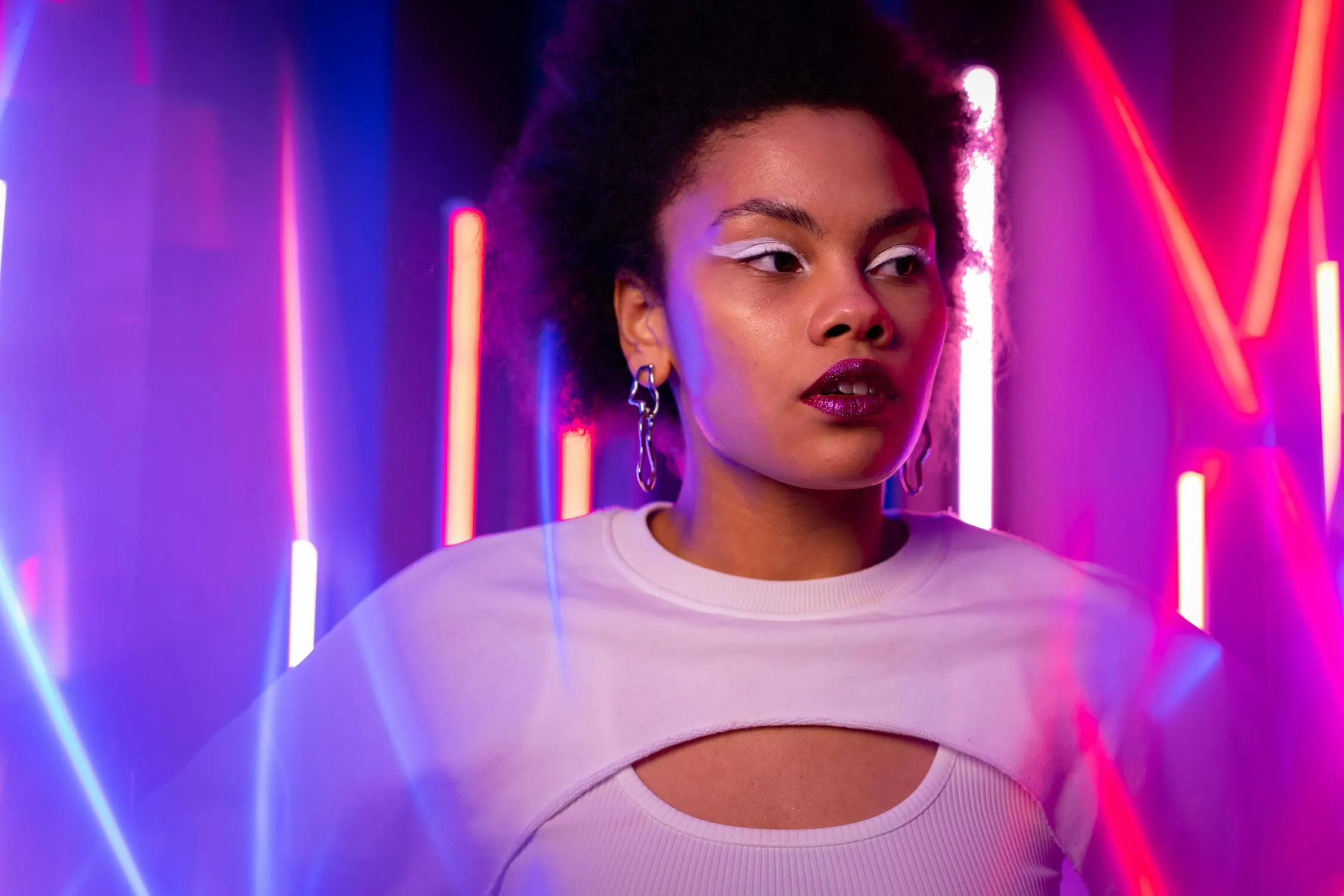 Woman in a White Top Standing in Neon Purple and Pink Lights