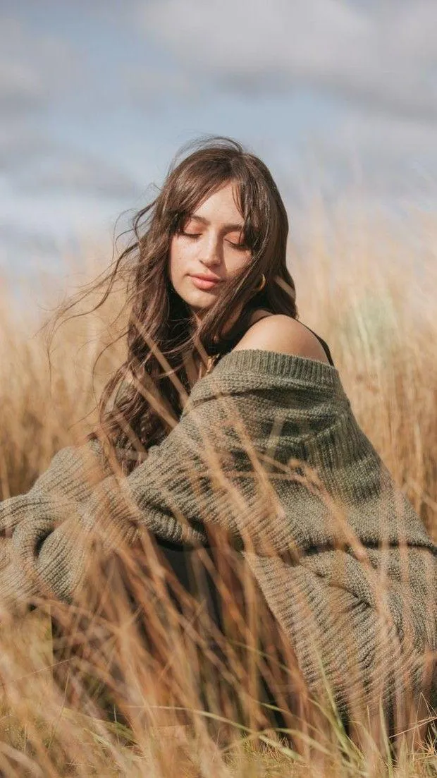 Woman Wrapped in a Cozy Blanket in a Field of Tall Grass