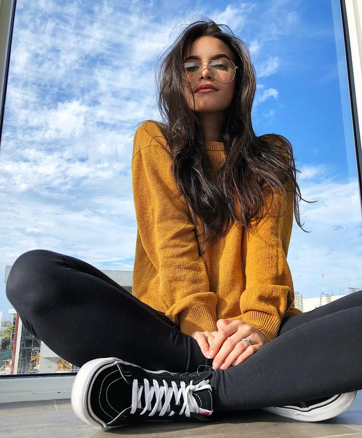 Woman in a Yellow Sweater Sitting Casually by the Wall Image