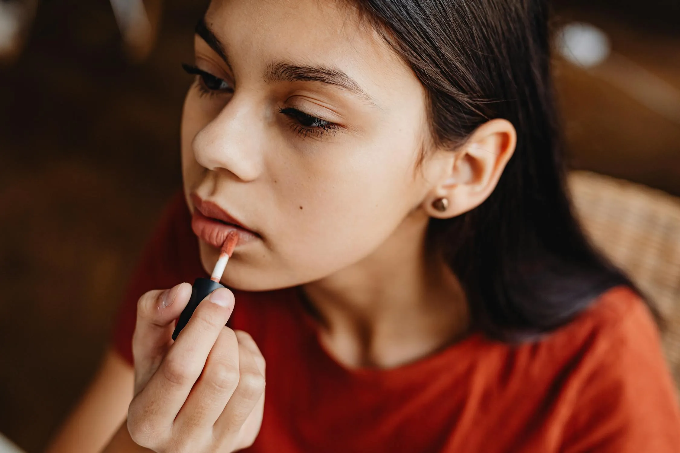Young Girl Applying Lipstick While Looking in the Mirror