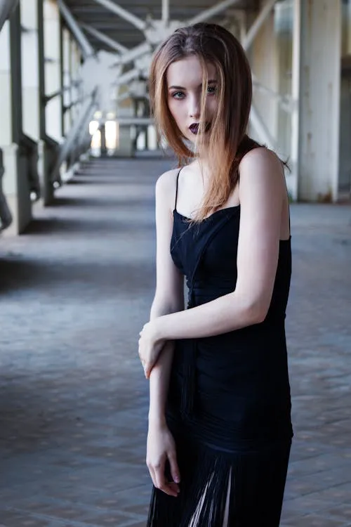 Young Woman in a Black Dress Standing on an Urban Walkway
