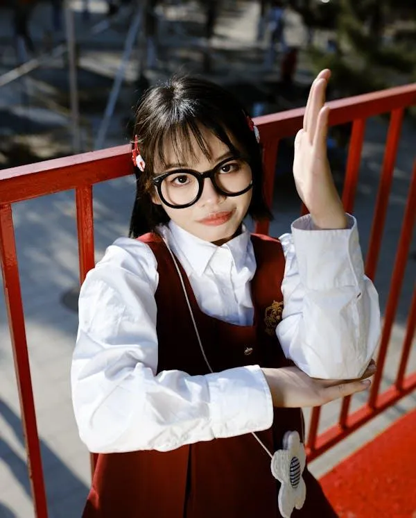 Young Woman in Glasses Smiling While Sitting on Red Stairs