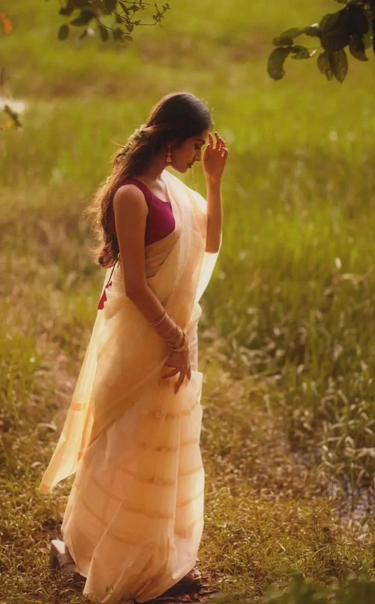 Young woman in a white saree standing in the grass field