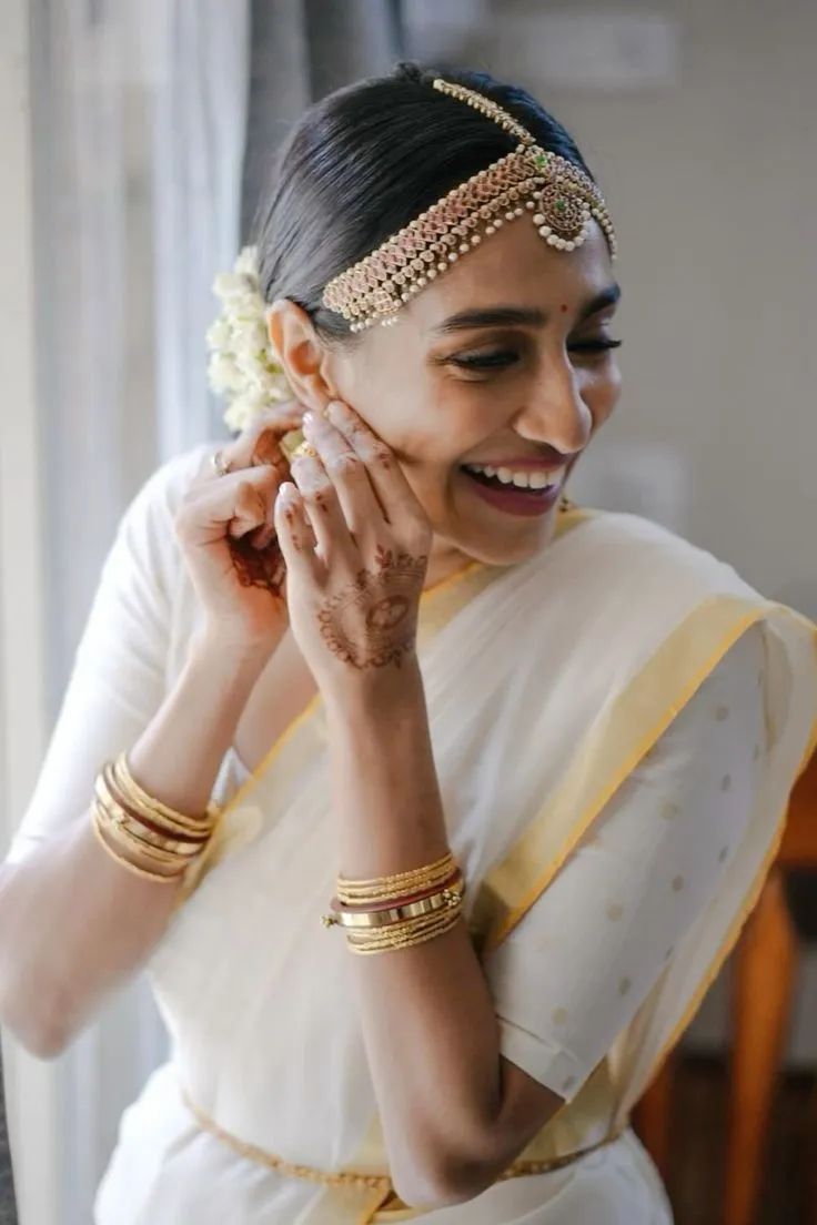 Young woman in a white saree with her hand on her ear image