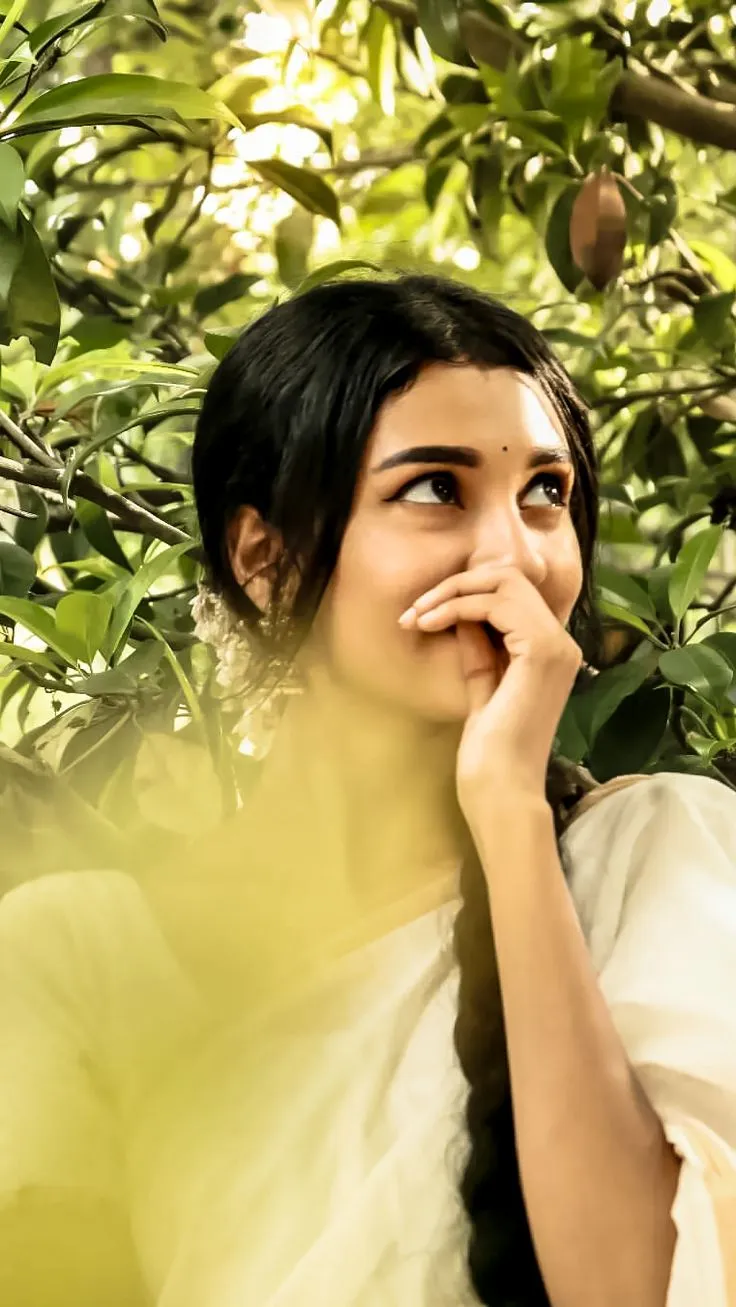 Young woman in an Onam saree standing near the green tree