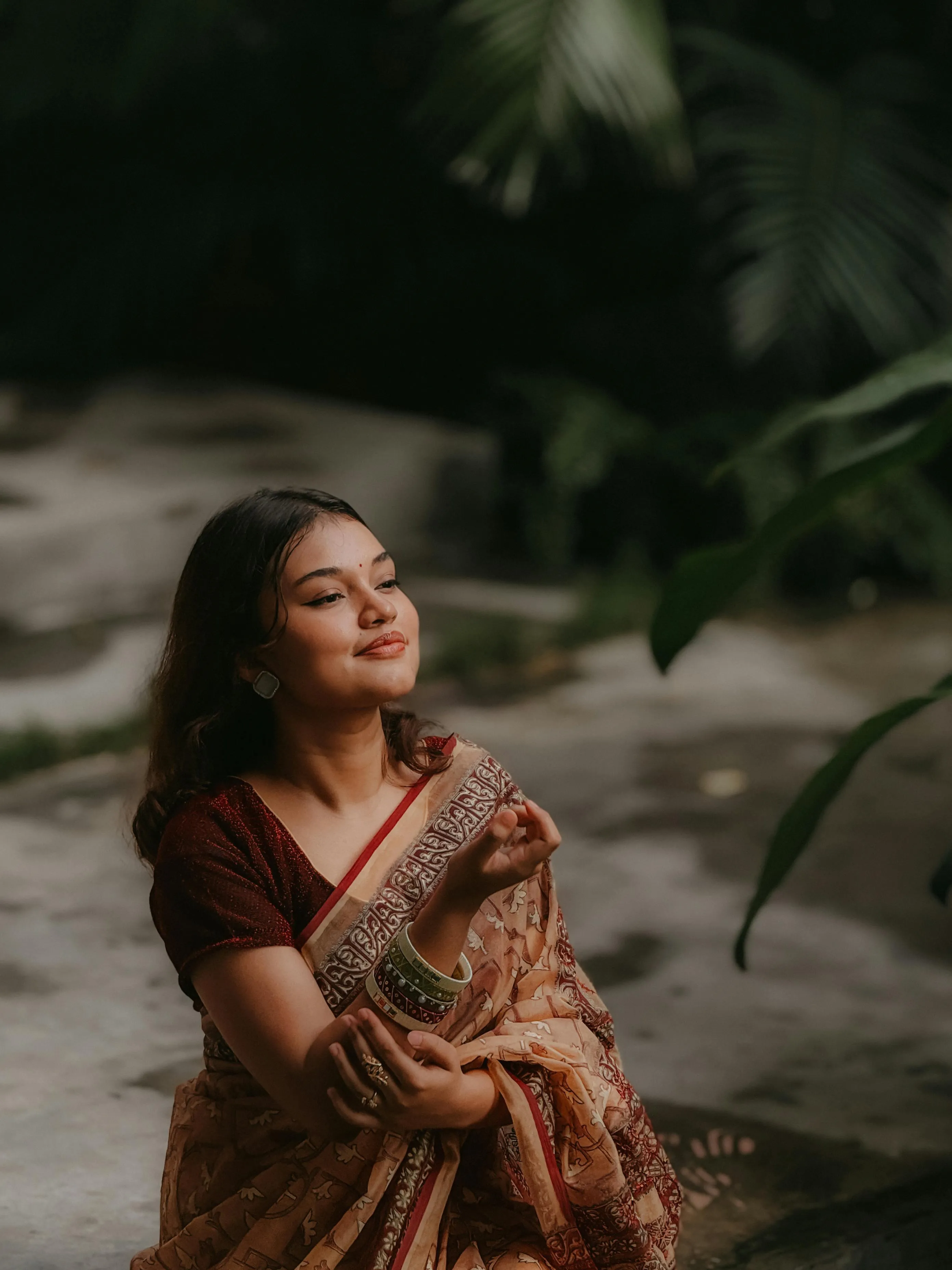 Young Woman in Brown Saree Sitting Peacefully Outdoors Image