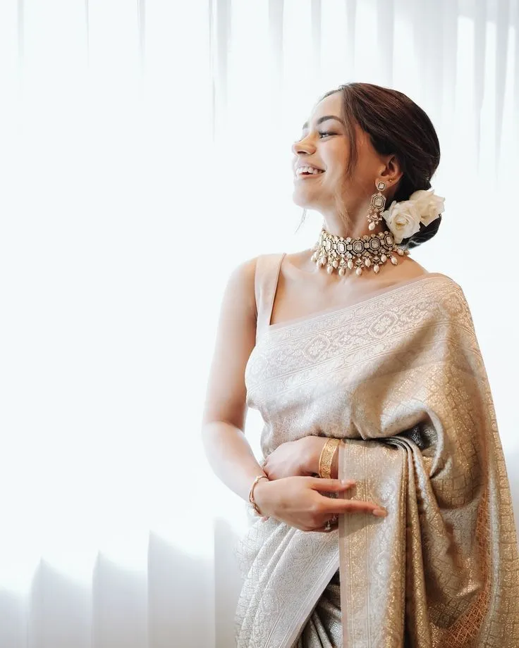 Young woman in Onam saree standing near a bright background