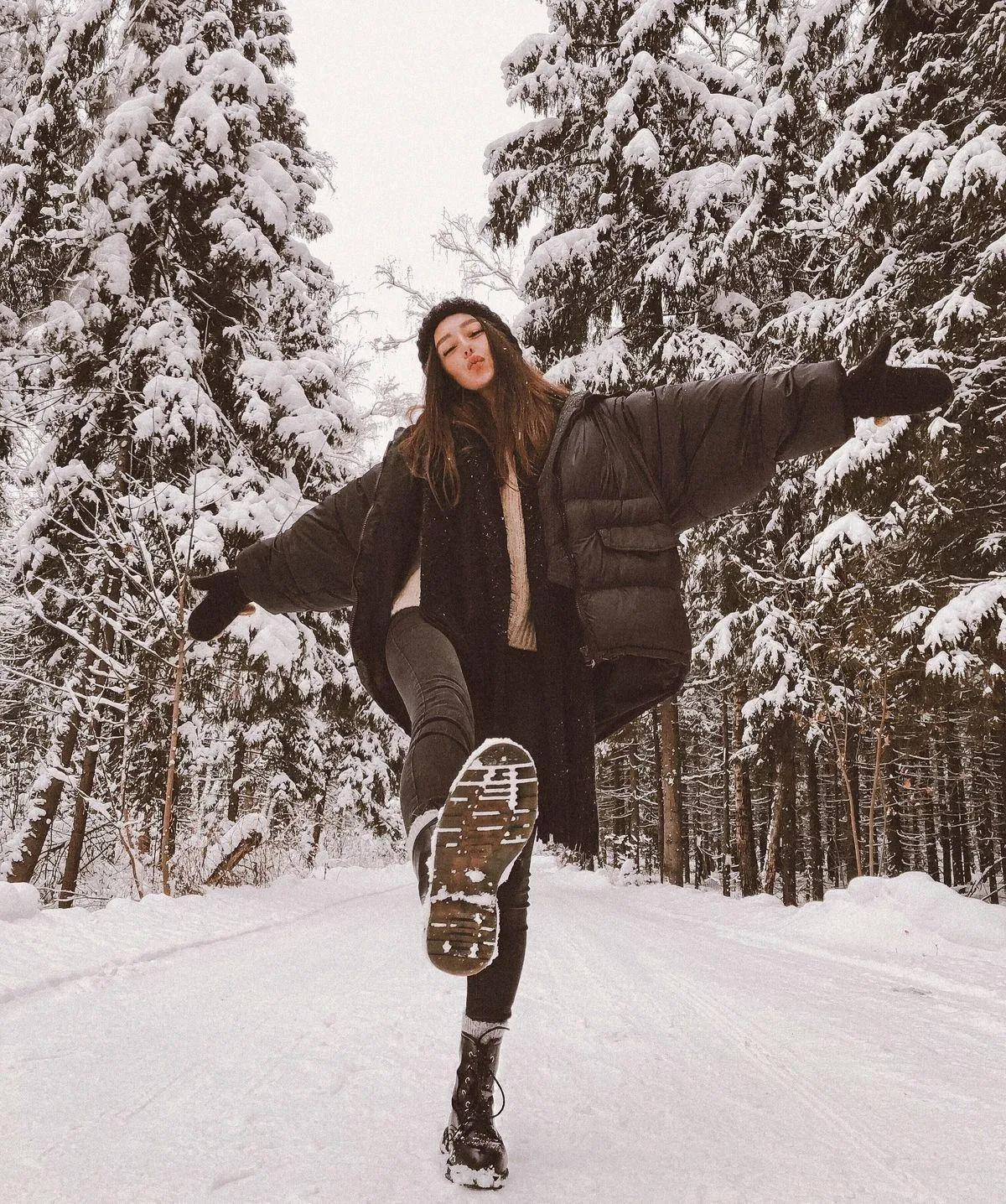 Young Woman Jumping in a Snowy Forest with a Winter Jacket