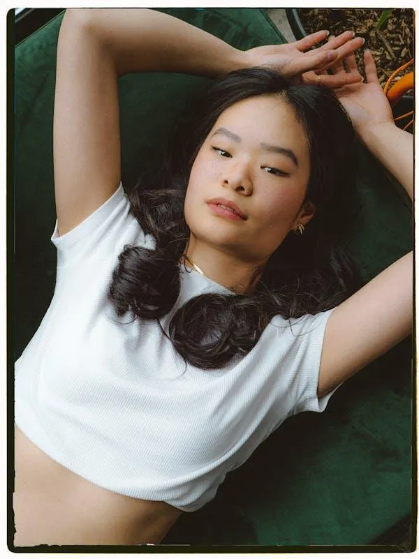 Young Woman Lying on the Grass with Her Hand Above Her Head