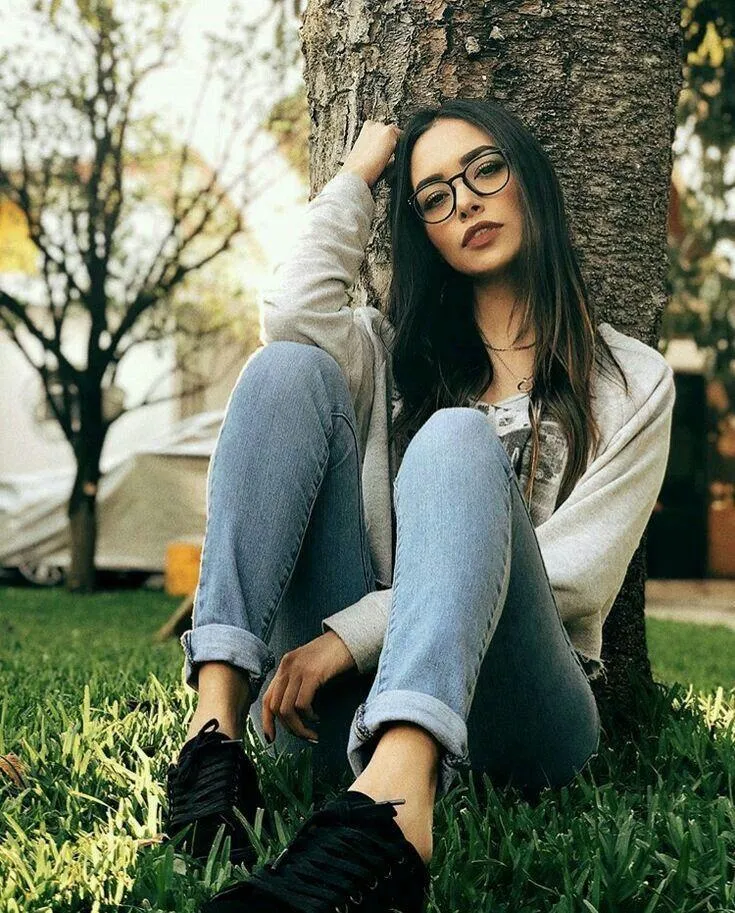 Young Woman Sitting Cross Legged on the Grass in a Park