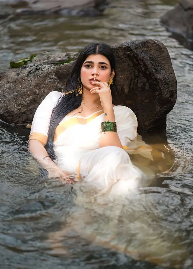 Young woman sitting in water with her hand on her lips image