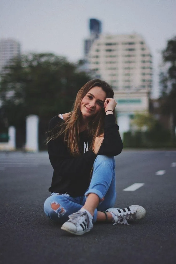 Young Woman Sitting in the Street with a City Background