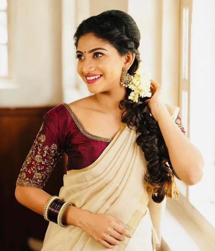 Young woman standing near the window wearing a Kerala saree