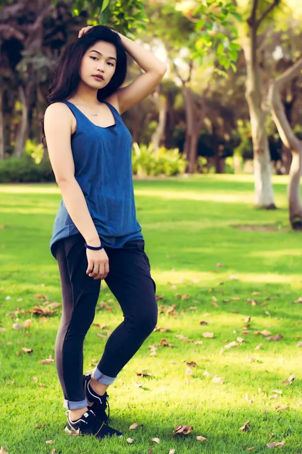 Young Woman Standing in a Park with Her Hand on Her Head