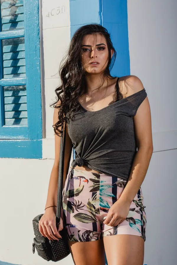Young Woman in Summer Outfit Posing Beside a White Building