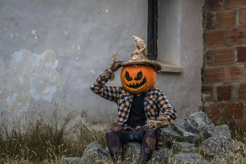 Boy with Pumpkin Head Sitting Outdoors in Halloween Costume
