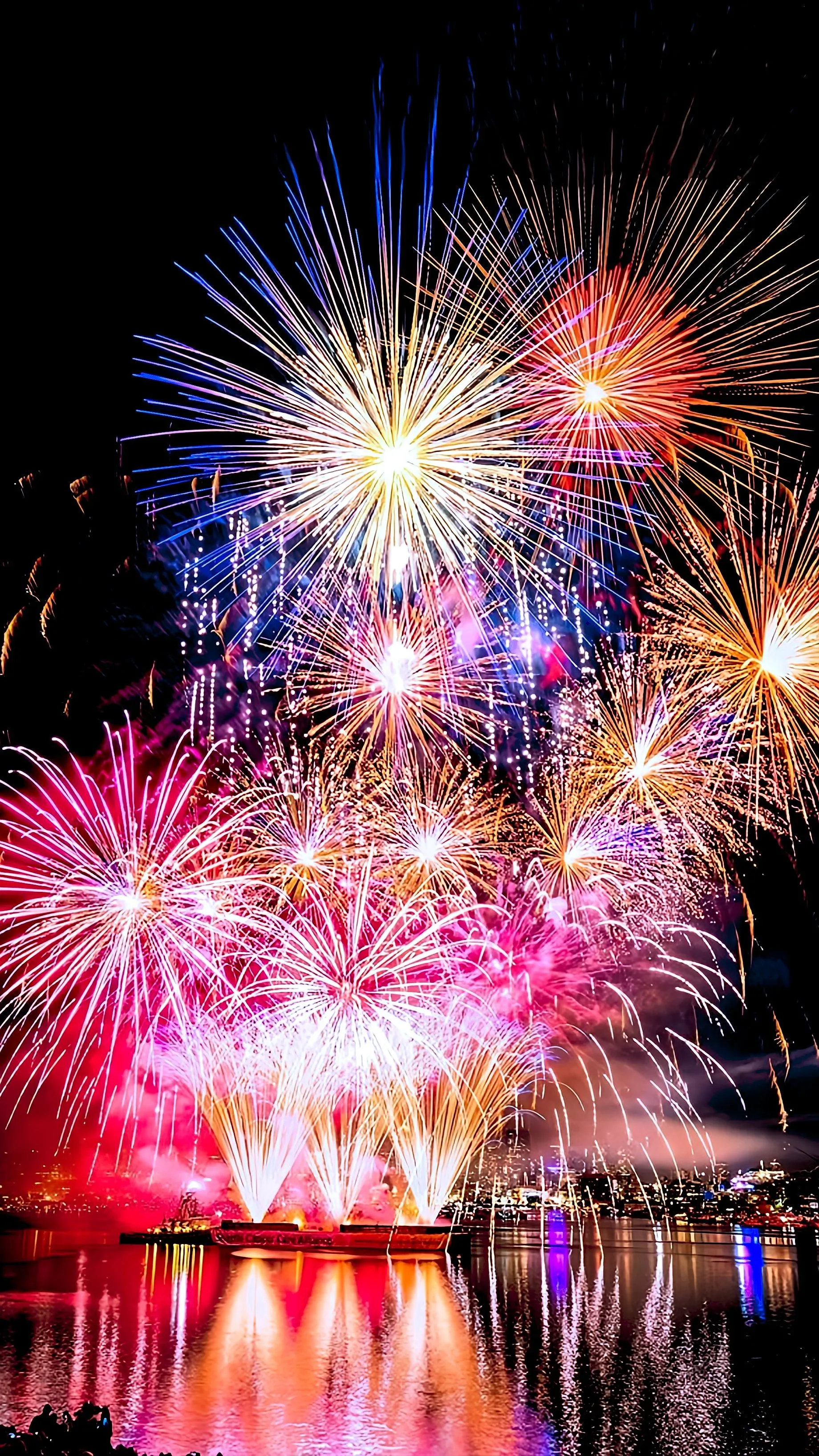 Bright fireworks bursting over the city skyline Wallpaper