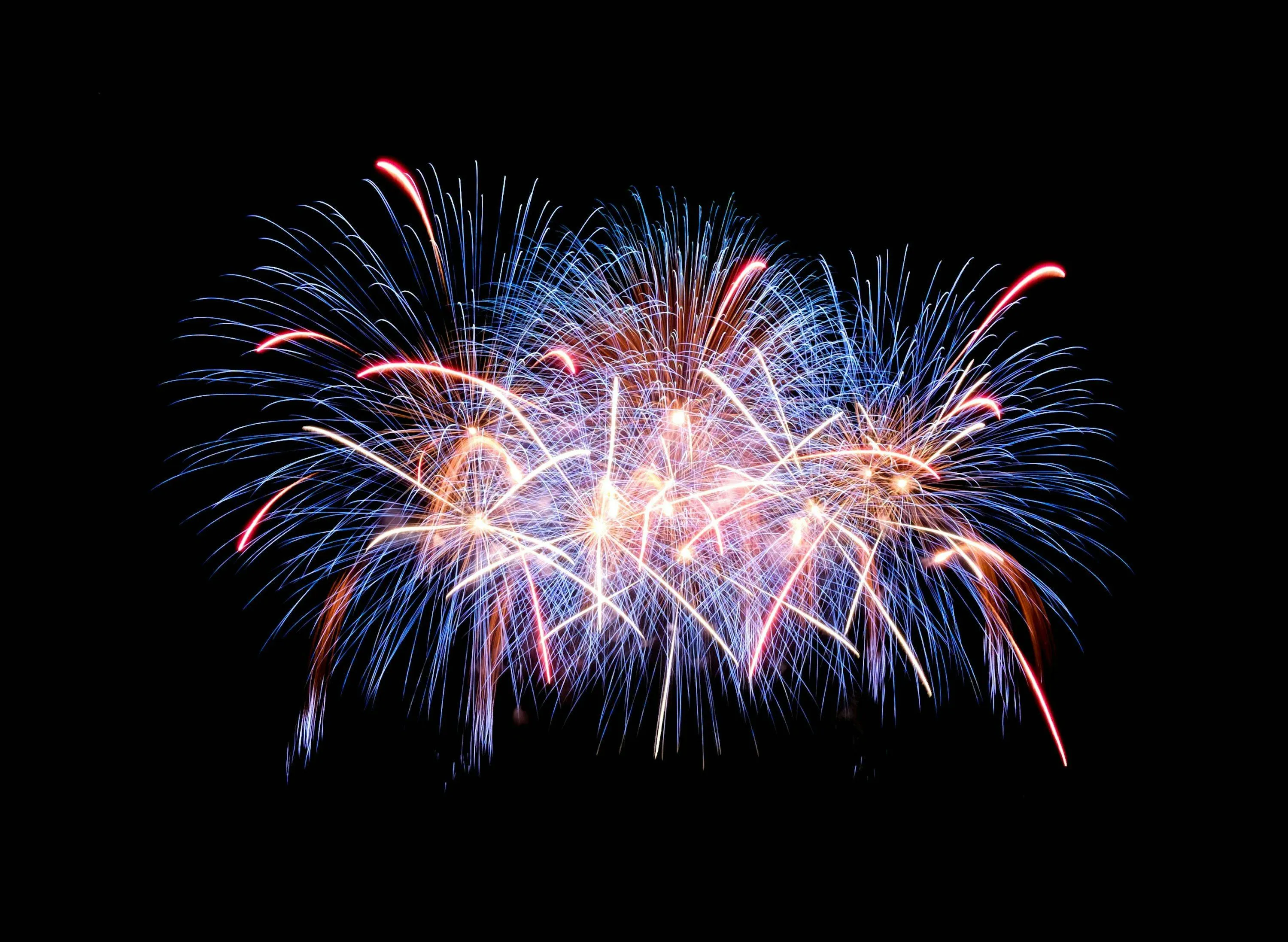 Bright fireworks creating colorful arcs in the night sky