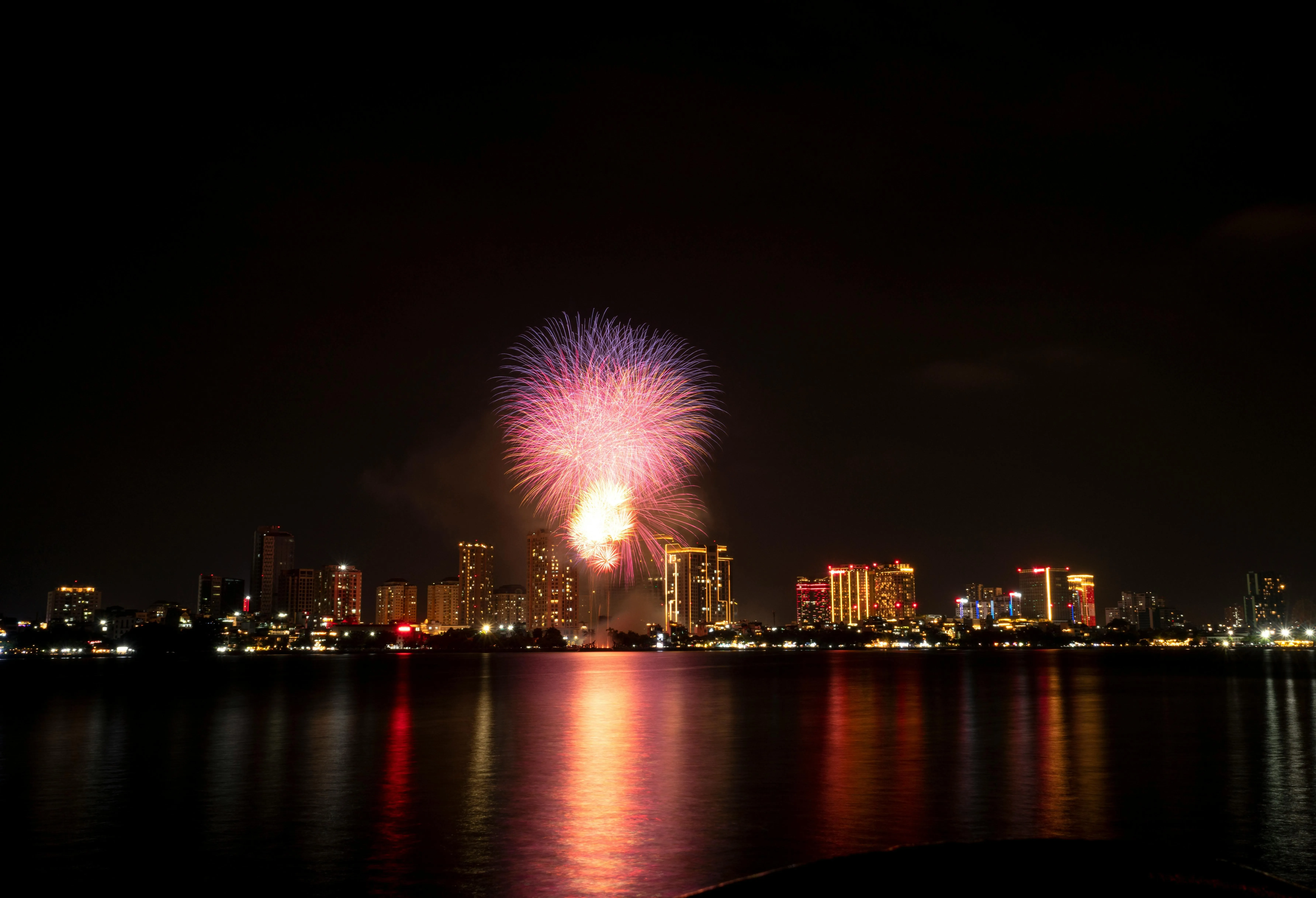 Bright Fireworks Reflecting on the Water at Night Wallpaper