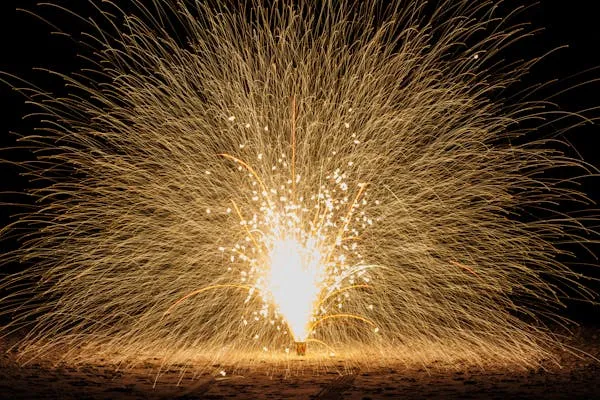 Bright golden fireworks exploding in the dark night sky