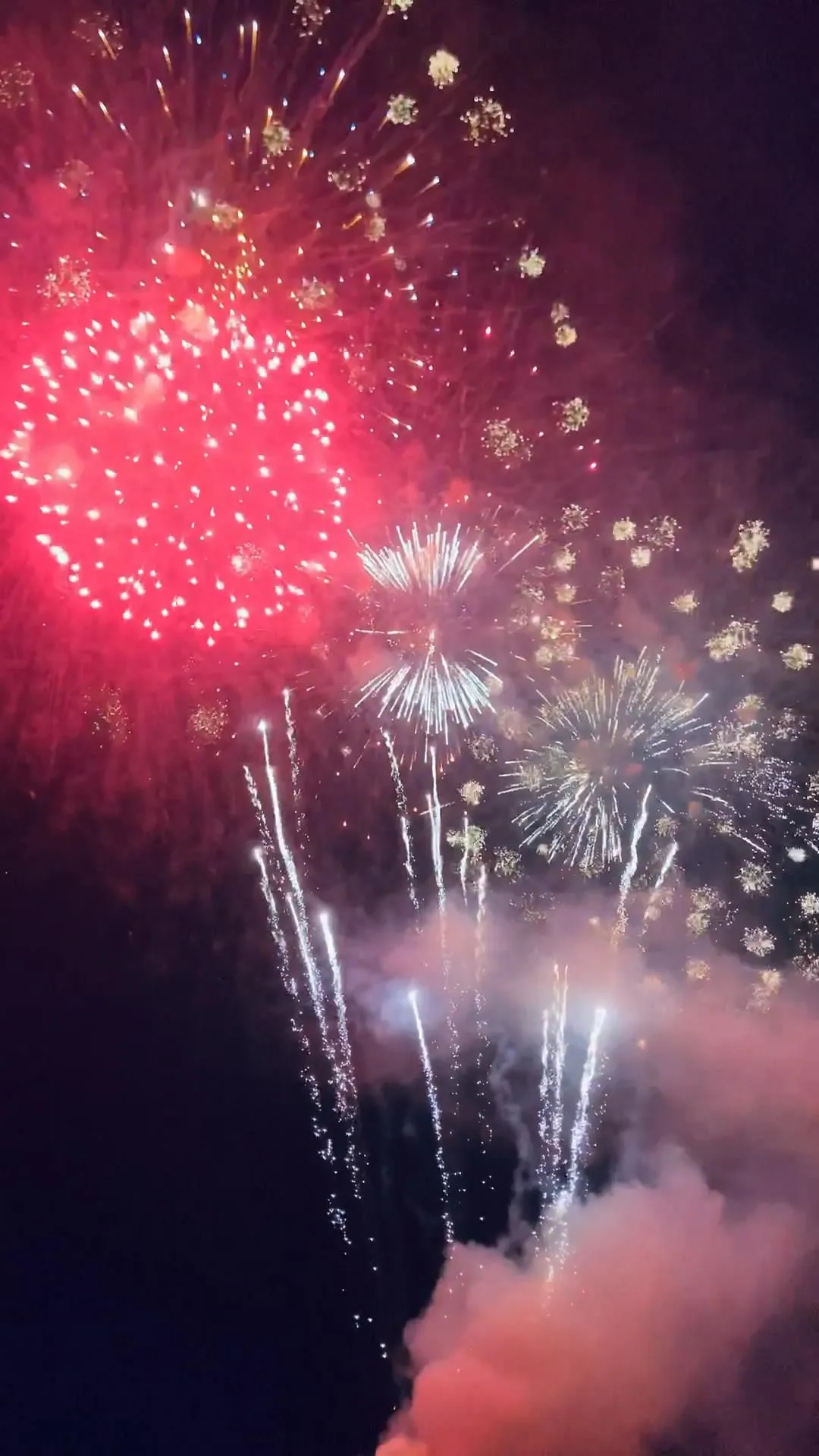 Bright red and white fireworks exploding over dark skies