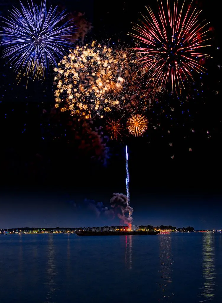 Brilliant fireworks explode over the water surface Wallpaper