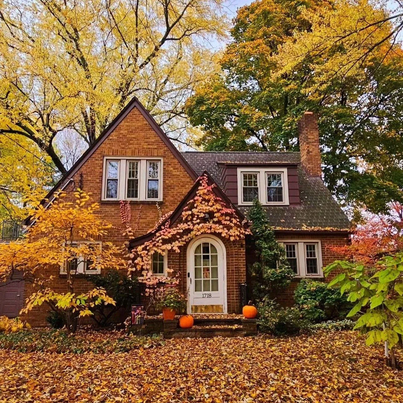 Charming House Surrounded By Autumn Trees and Pumpkin Decor