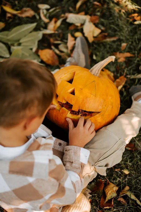 Child Carving Pumpkin in Warm Outdoor Halloween Scene