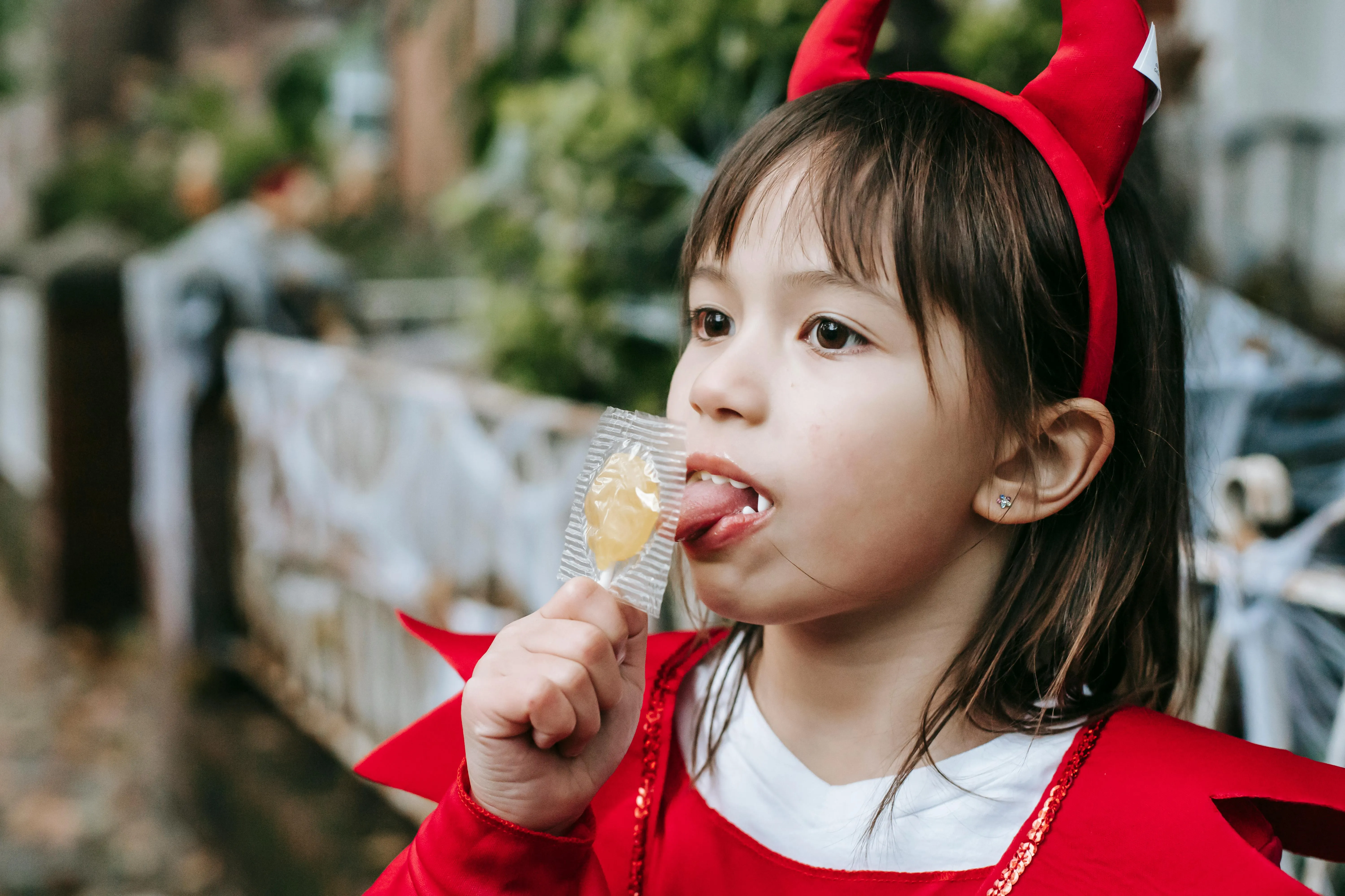 Child Dressed as Devil Eating Lollipop at Halloween