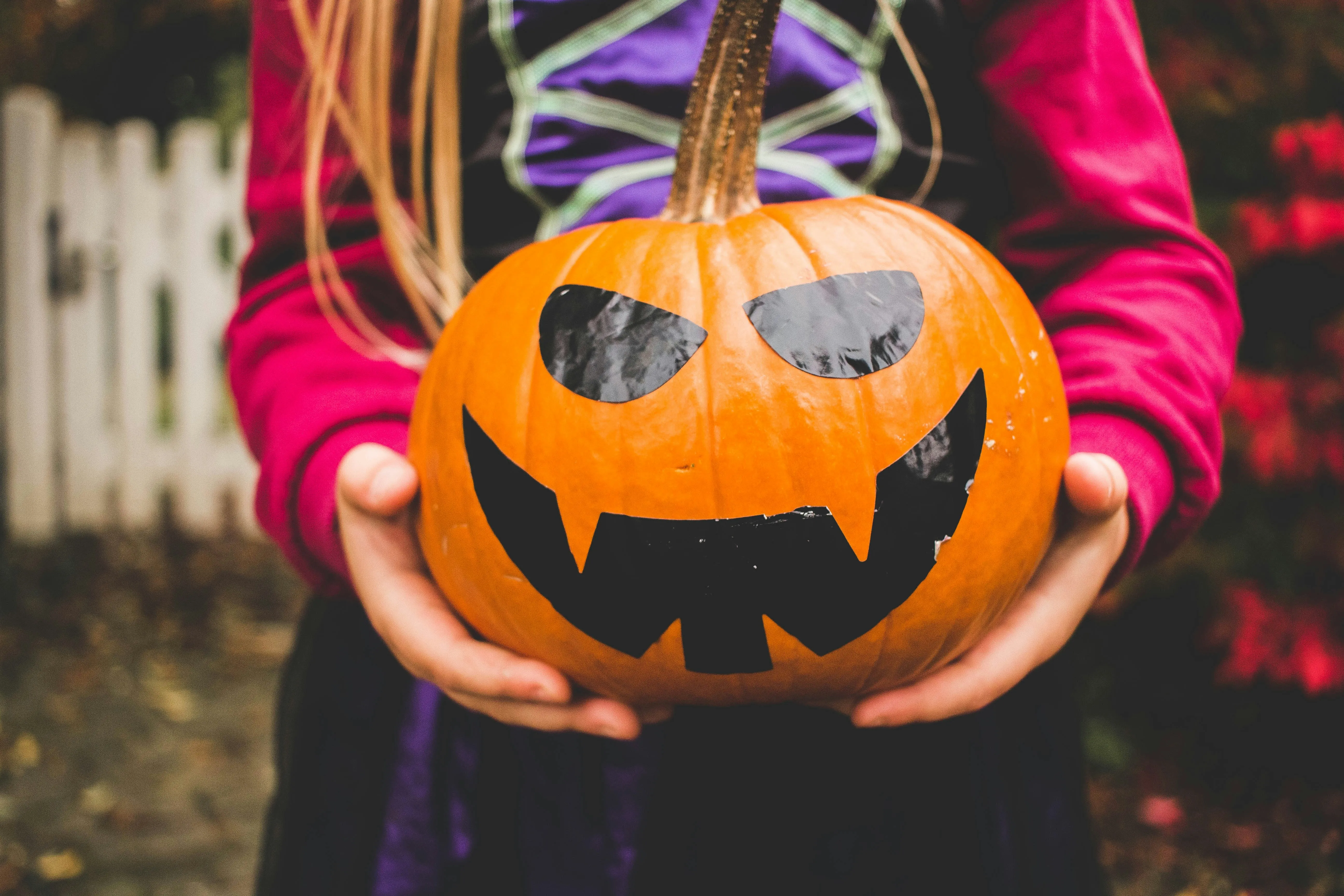 Child Holding Carved Pumpkin with Candy Inside Wallpaper